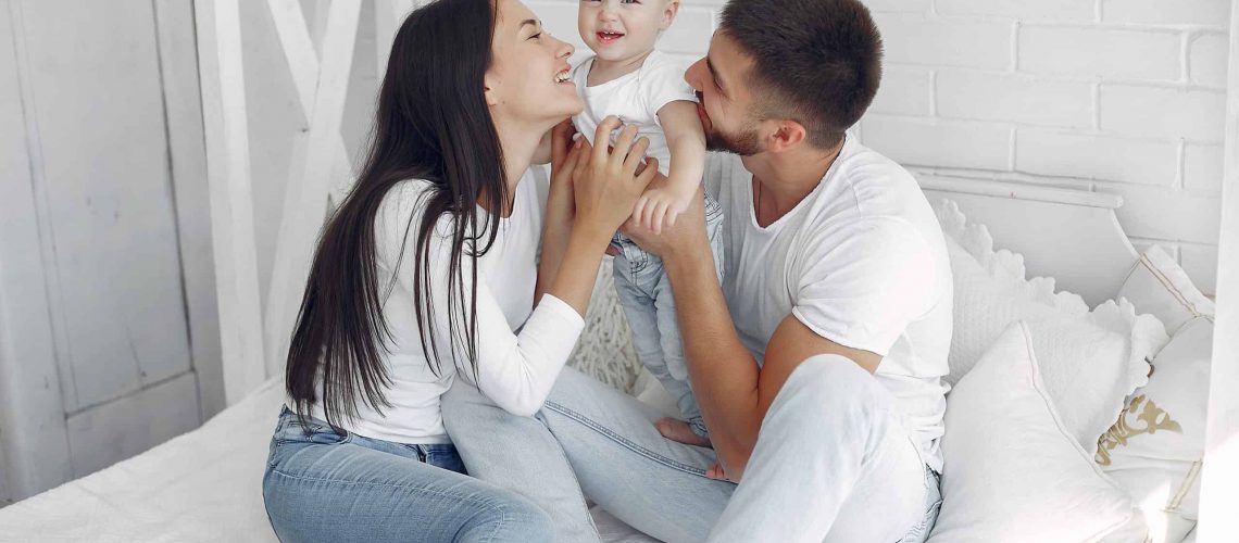 Cute family in a room. Lady in a white shirt. Little boy with parents